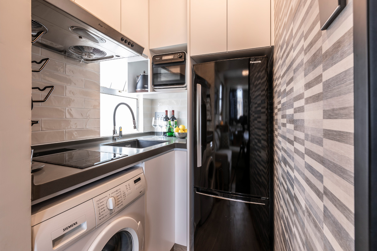 The kitchen is also the laundry room and the black and white palette suits it