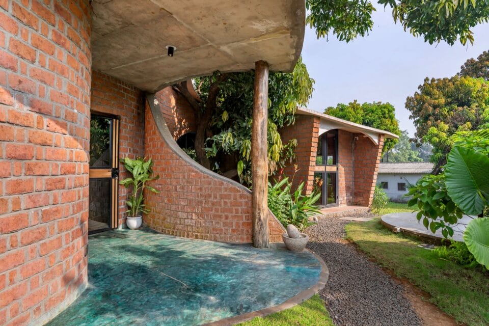 a photo of a brick home that curves around a tree