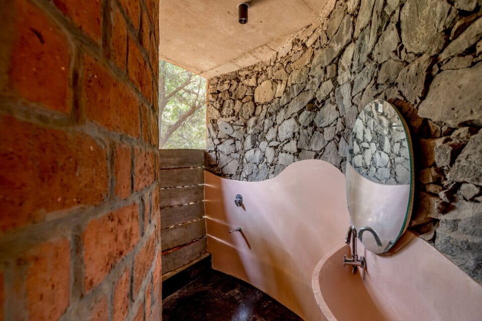 a pink cement sink in a bathroom with a mirror and brick and stone walls