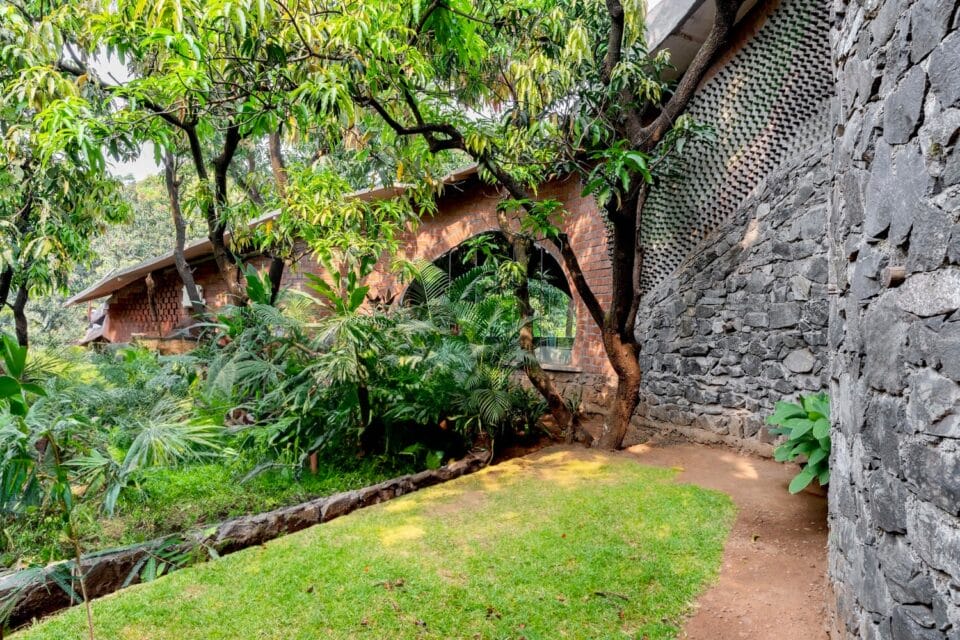 the exterior of a home made of stone and brick that wraps around a tree