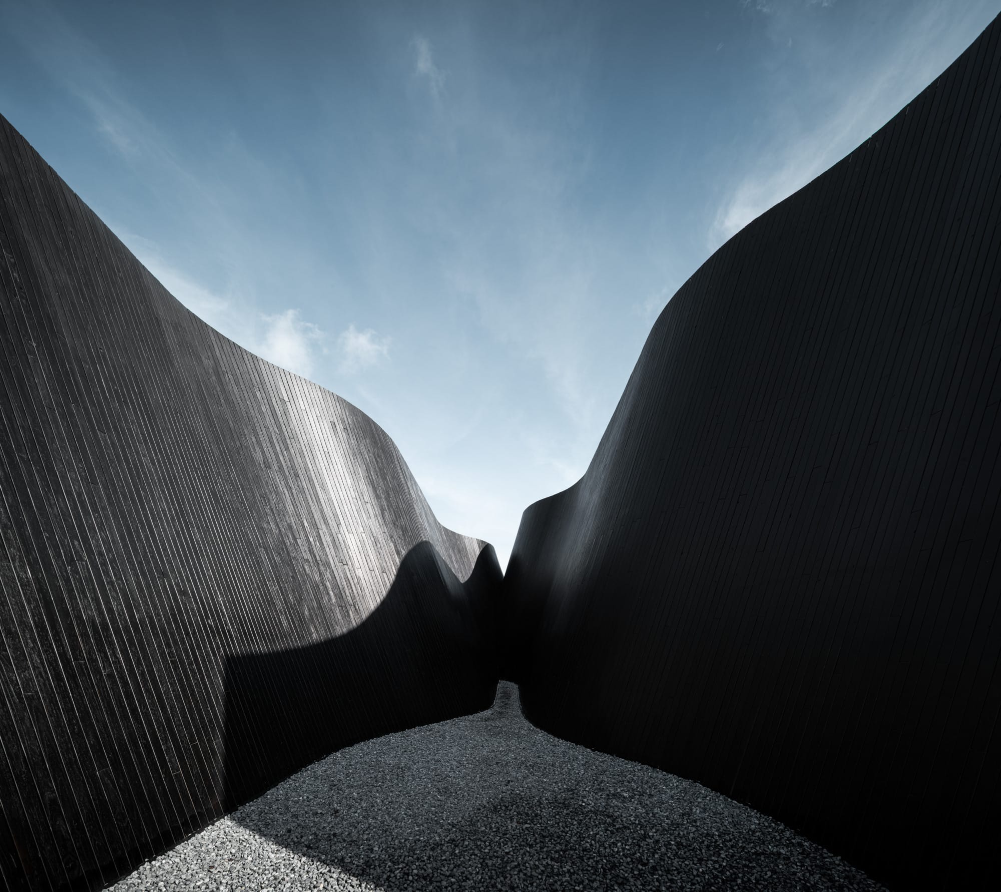 an image of two undulating black walls of a contemporary coffee shop, constructed of black vertical timber