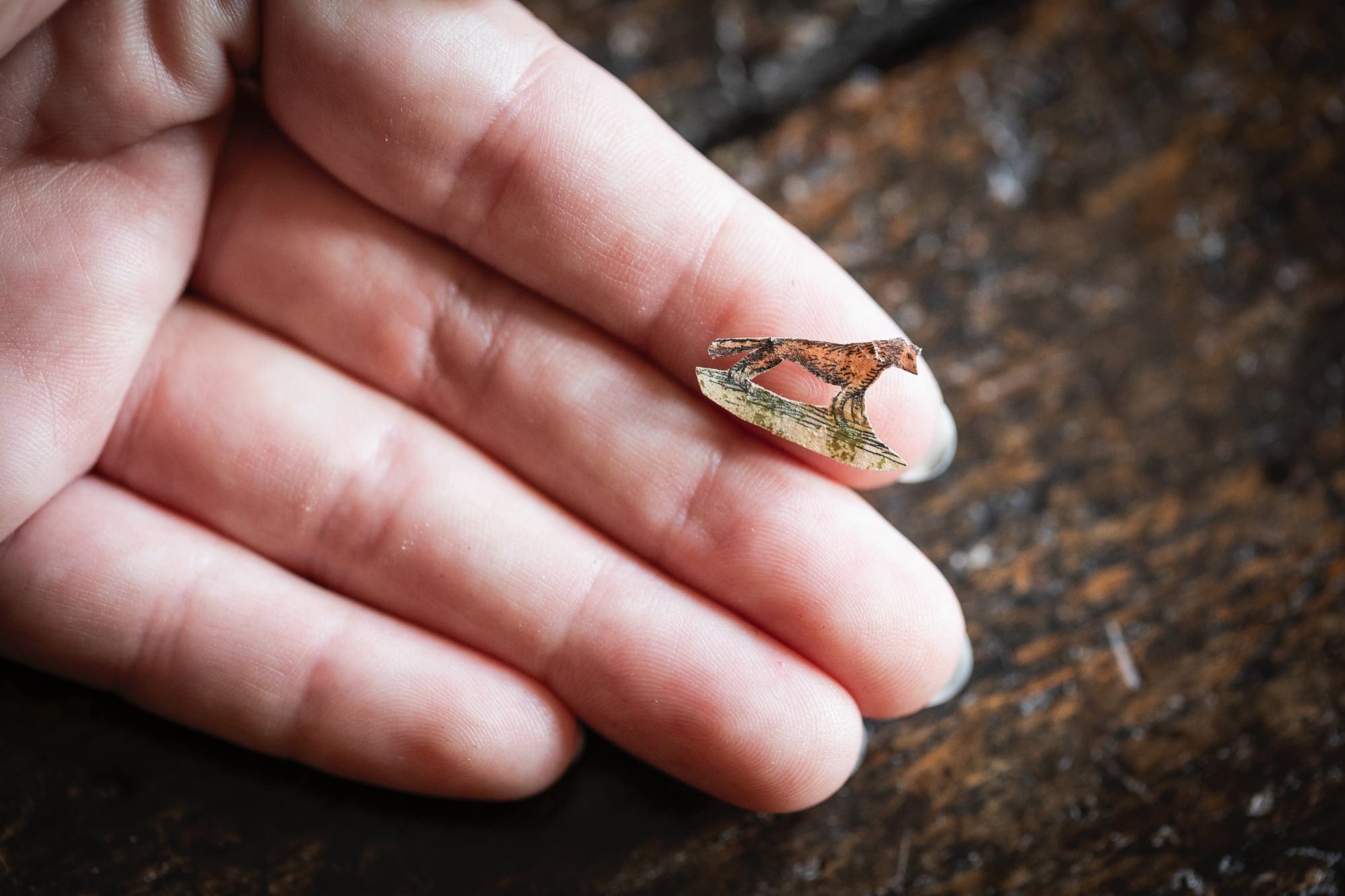 a white hand holding a papercut of a fox