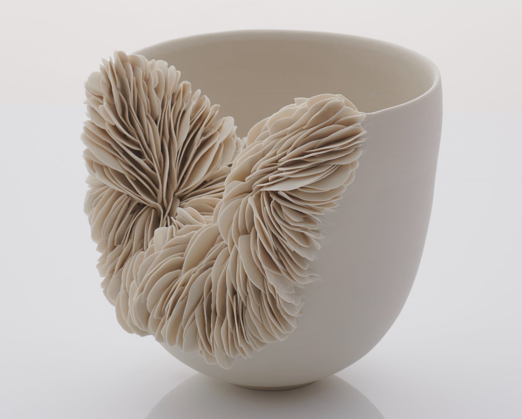 a white porcelain vessel that erupts into innumerable layered fragments